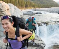 Couple carrying a backpack along a river