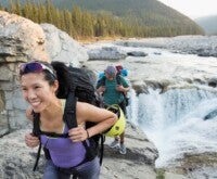 Couple carrying a backpack along a river