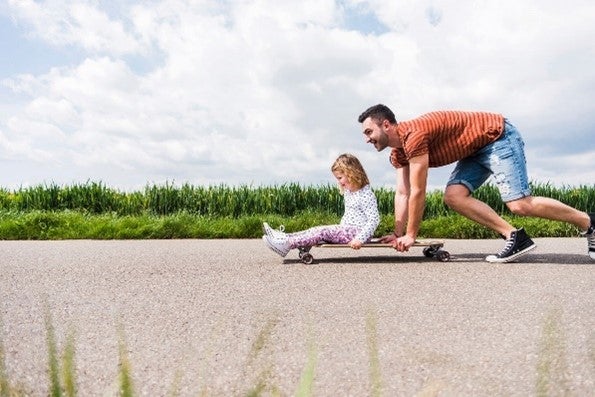 Man pushing her daughter on skateboard