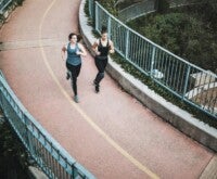 Two females running on a bridge