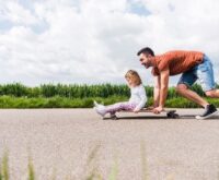 Man pushing her daughter on skateboard