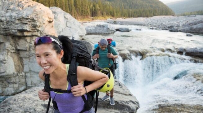 Couple carrying a backpack along a river