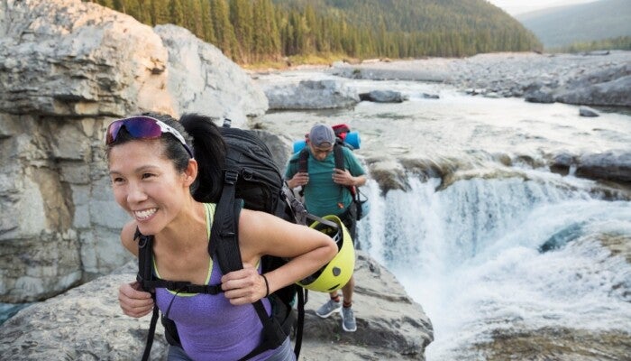 Couple carrying a backpack along a river