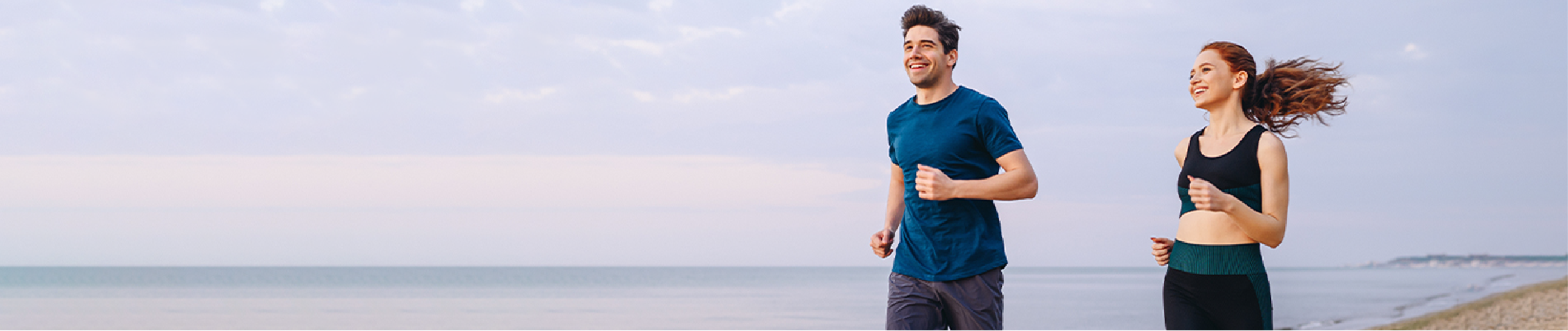 A happy couple enjoys a morning jog along the seaside