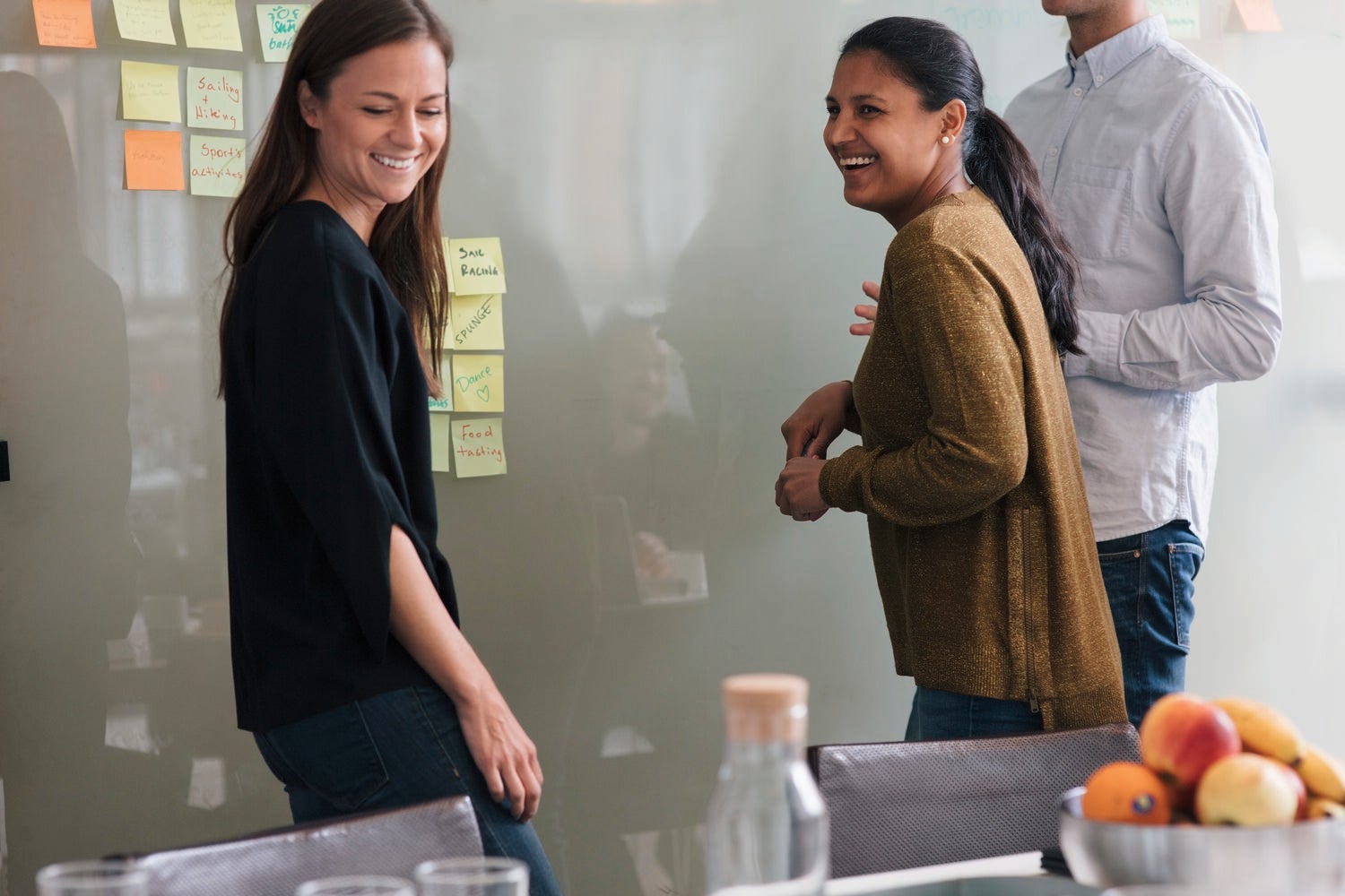 Cheerful female coworkers standing by male colleague in board room at office