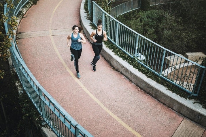 Two females running on a bridge