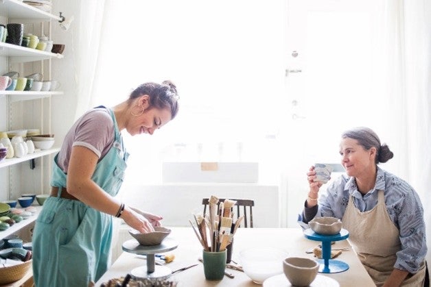 Two females talking over pottery making