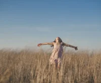 Women wearing pink dress is spinning in a field